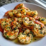 A close-up of seasoned and cooked air fryer shrimp tossed in butter and fresh parsley.