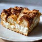 Close-up of a square slice of overnight french toast casserole with a thick cream cheese layer.
