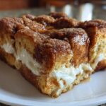 A close-up of a square slice of amazing french toast casserole with creamy filling.