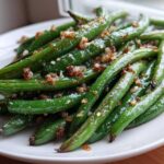 Close-up of bright green beans roasted at 400° and topped with crispy browned garlic bits.