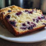 Close-up of two thick slices of moist blueberry banana bread showing juicy blueberries baked into the crumb.