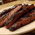 Close-up of perfectly grilled and sliced steak, showing a medium-rare center, prepared with carne asada marinade.