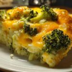 Close-up of a serving of cheesy broccoli rice, topped with melted cheddar cheese and bright green broccoli florets.