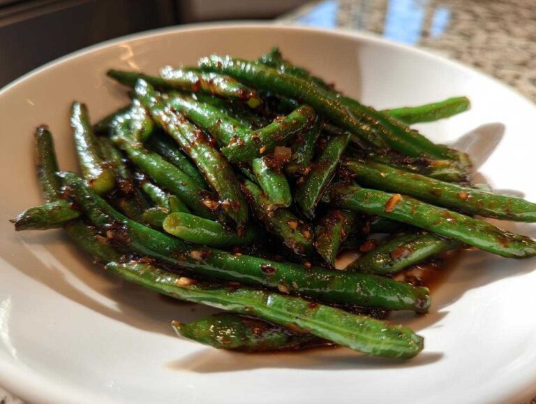 Close-up of vibrant chinese green beans with garlic sauce served in a white bowl.