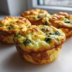 Four golden-brown cottage cheese egg cups with visible spinach, baked until fluffy.