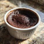 A rich, dark chocolate Cottage Cheese Microwave Brownie baked in a white ramekin, sitting on a granite countertop.