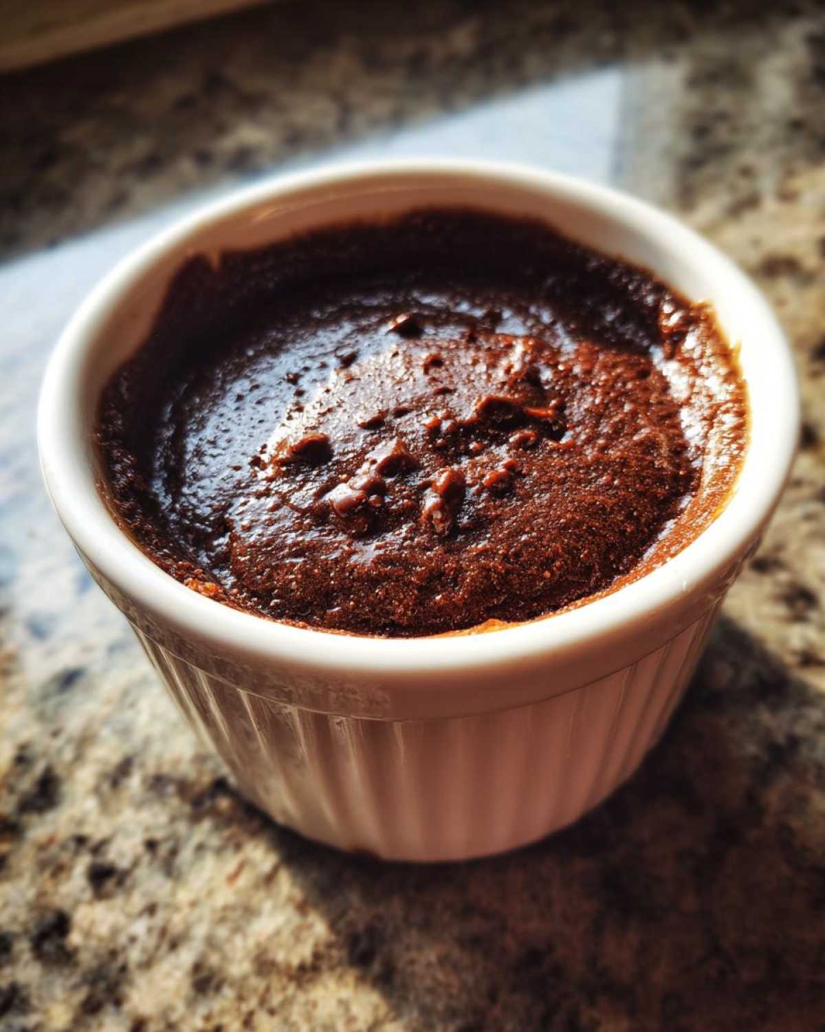 A rich, dark chocolate Cottage Cheese Microwave Brownie baked inside a white fluted ramekin.