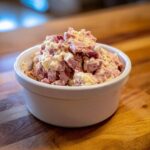 Close-up of creamy ham salad with diced ham and dressing served in a small white bowl.