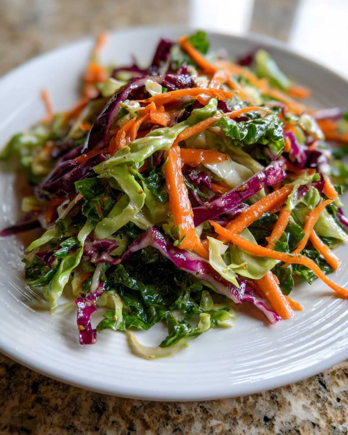 Close-up of a vibrant, crunchy cabbage salad featuring shredded green and purple cabbage and bright orange carrots.