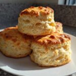 A stack of four tall, fluffy, golden brown scones showcasing their flaky layers, ready to eat.