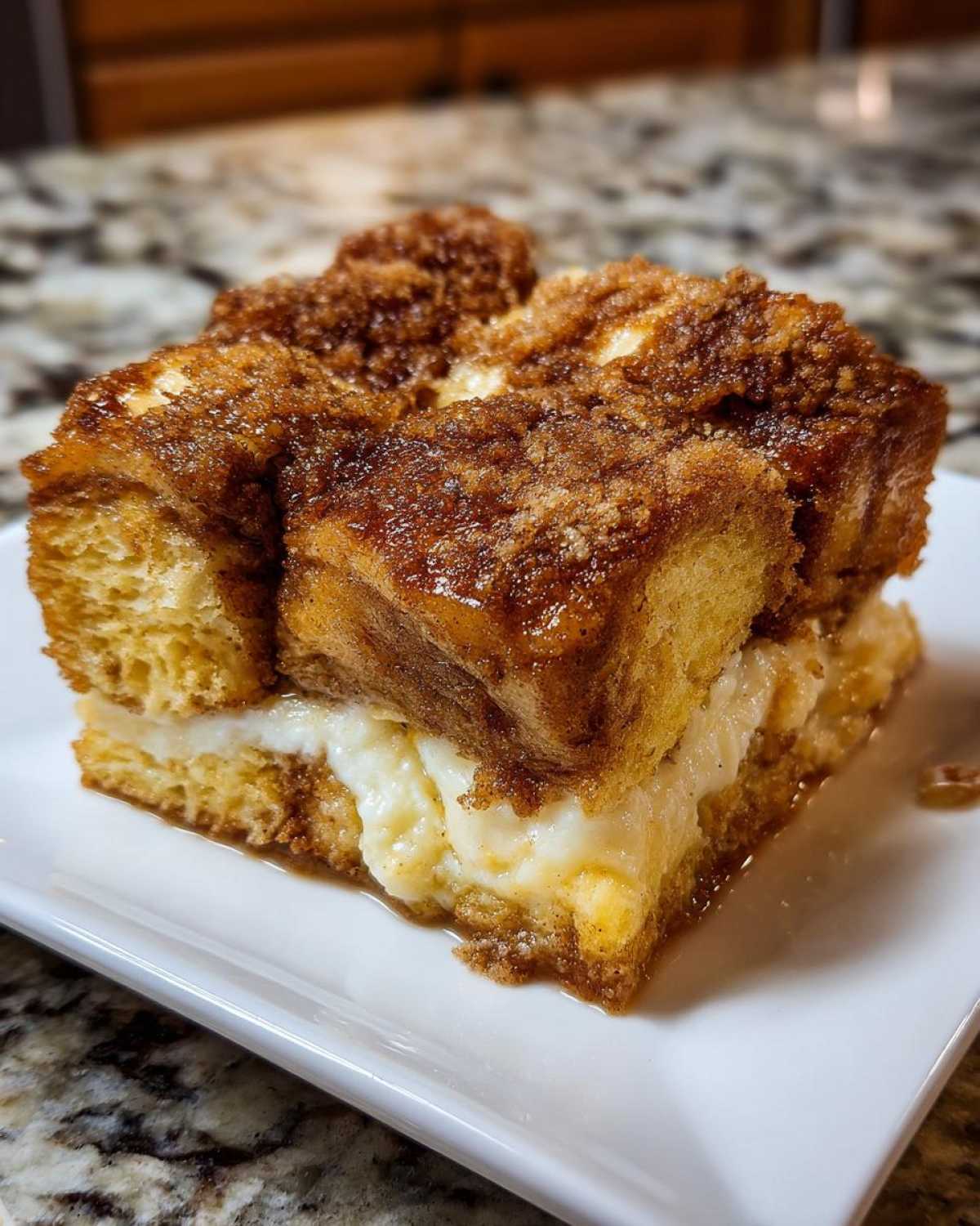 A close-up of a square slice of rich french toast casserole with a creamy filling and cinnamon streusel topping.