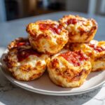 A stack of freshly baked pizza muffins with melted cheese and tomato sauce topping.