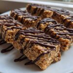 Close-up of several homemade protein bars made with oats and drizzled generously with dark chocolate.