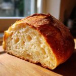 A close-up of a freshly cut loaf of Italian bread showing a light, airy crumb and golden crust.