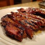 Close-up of perfectly grilled and sliced steak showing a medium-rare center, achieved with the carne asada marinade.