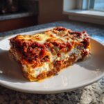 A close-up, appetizing slice of Lasagna with Cottage Cheese, showing rich meat sauce and creamy white layers.