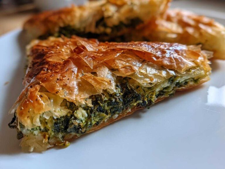 Close-up of a flaky slice of Mediterranean Spinach and Feta Cheese Crisps showing the golden phyllo dough and green filling.