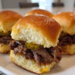 Four irresistible mississippi pot roast sliders piled high with shredded beef and pickles on soft buns.