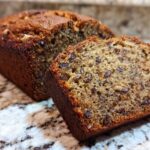 Close-up of a moist slice cut from a loaf of date nut bread, showing rich color and visible nuts/dates.