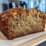 Close-up of a thick slice of moist sugar free banana bread showing its crumb texture and caramelized top.