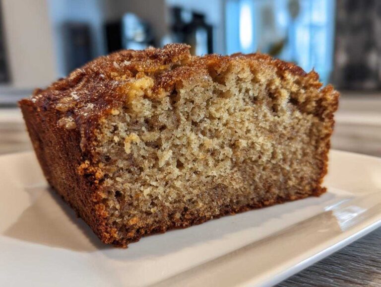 Close-up of a thick slice of moist sugar free banana bread showing its crumb texture and caramelized top.