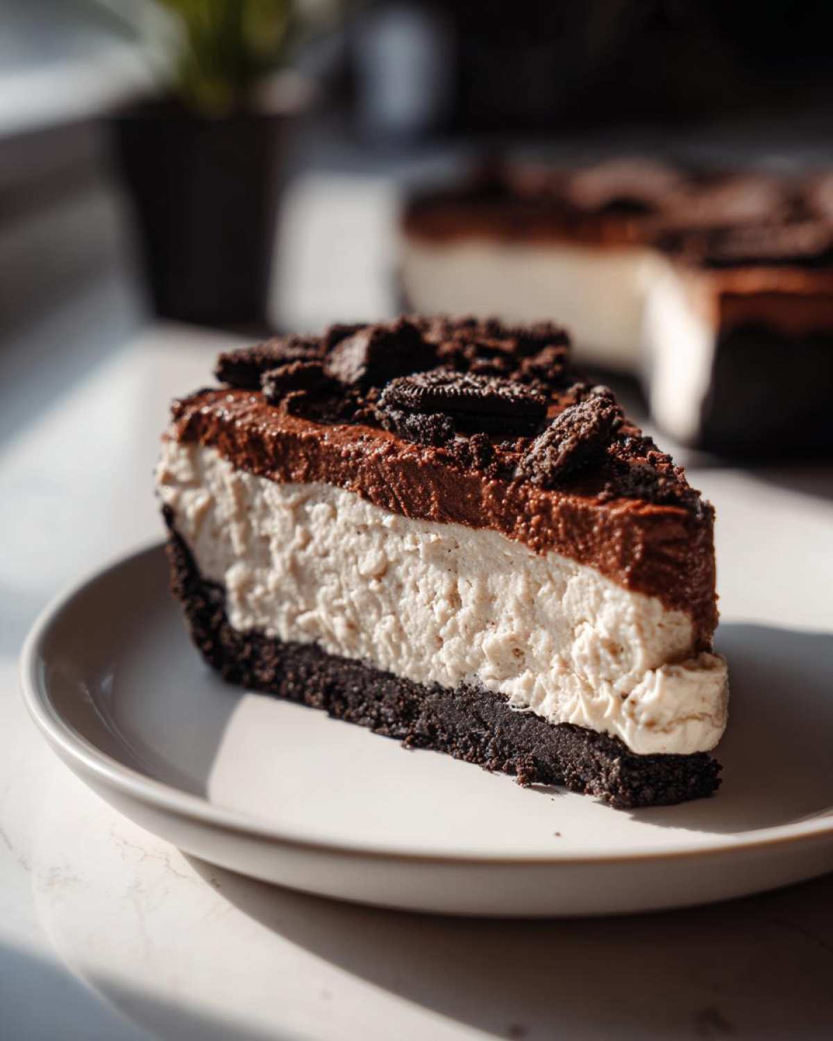 A decadent slice of no-bake Oreo pie featuring a dark crust, white filling, chocolate topping, and crushed Oreos.