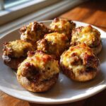 Close-up of seven golden brown sausage stuffed mushrooms topped with melted, bubbly cheese.