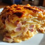 A close-up of a rich, cheesy slice of scalloped potatoes and ham with a golden-brown crust.