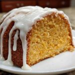 A close-up of a moist slice of sweet potato pound cake topped with thick white vanilla glaze.