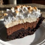 A decadent slice of 5-layer mud pie showing a dark crust, chocolate mousse, vanilla layer, and toasted mini marshmallows on top.