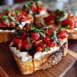 Close-up of a piece of toasted bread topped with white cheese, diced tomatoes, basil, and balsamic glaze, resembling a bruschetta dip serving.
