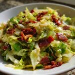 A close-up of a white bowl filled with sautéed cabbage and crispy bacon pieces, showcasing this amazing cabbage recipe.