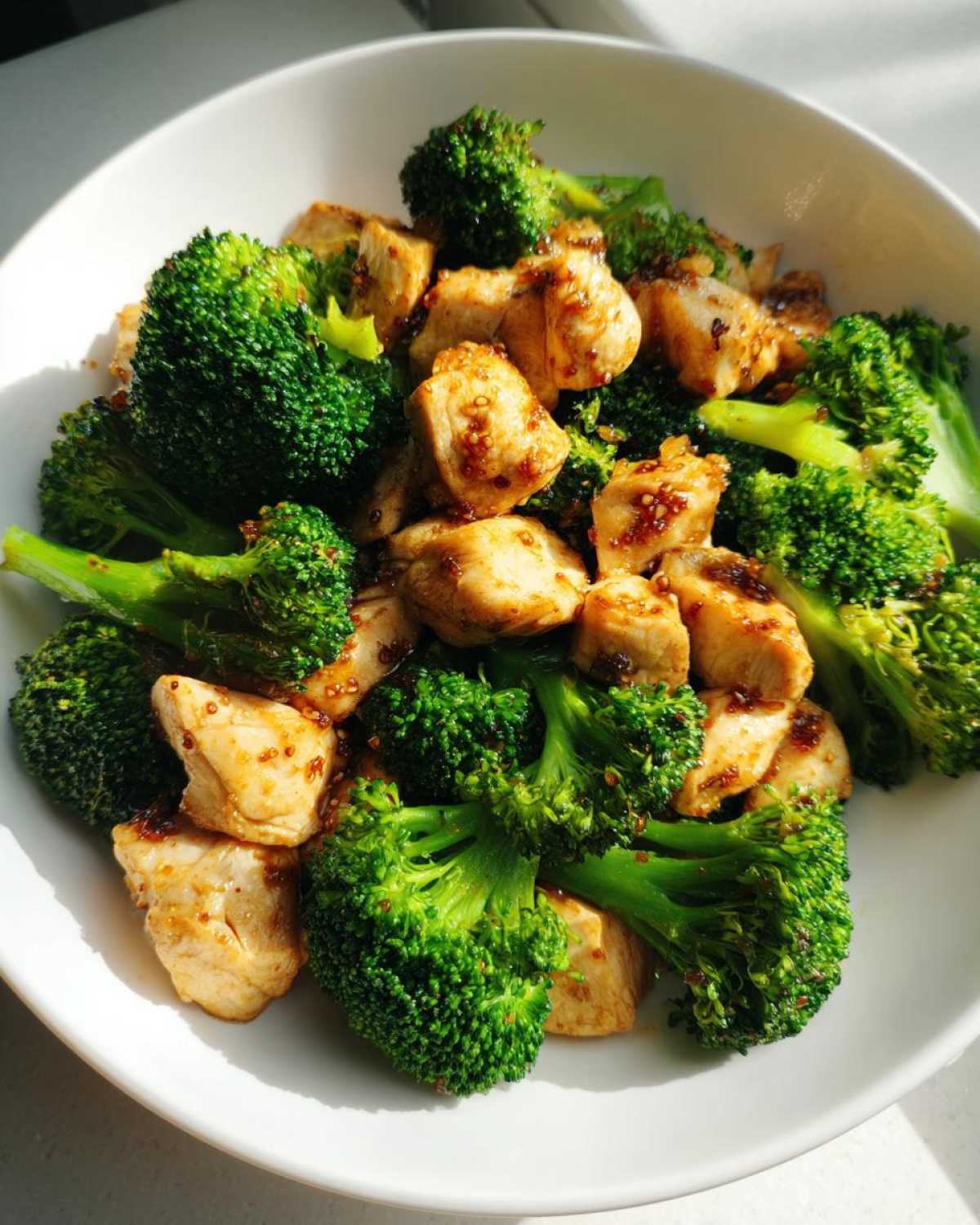Close-up of vibrant green broccoli florets mixed with golden pieces of seasoned chicken and broccoli.