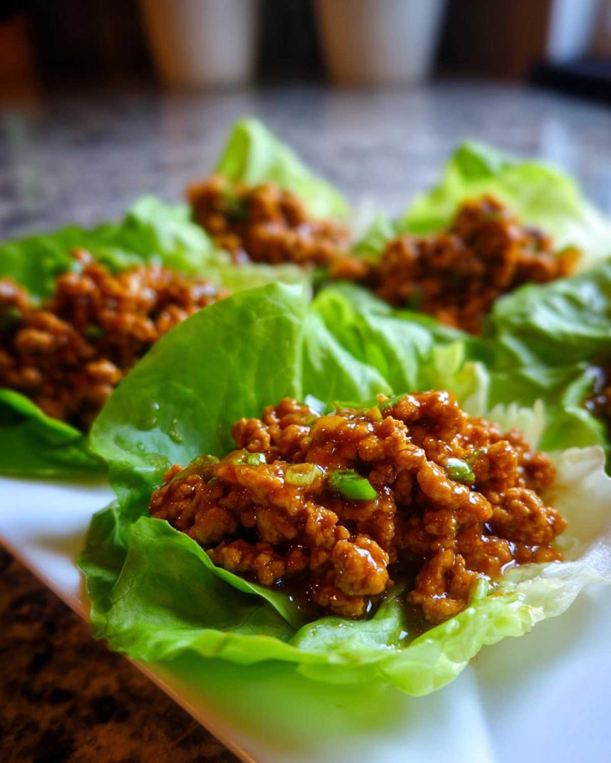 Close-up of several fresh chicken lettuce wraps filled with savory, saucy ground chicken mixture.