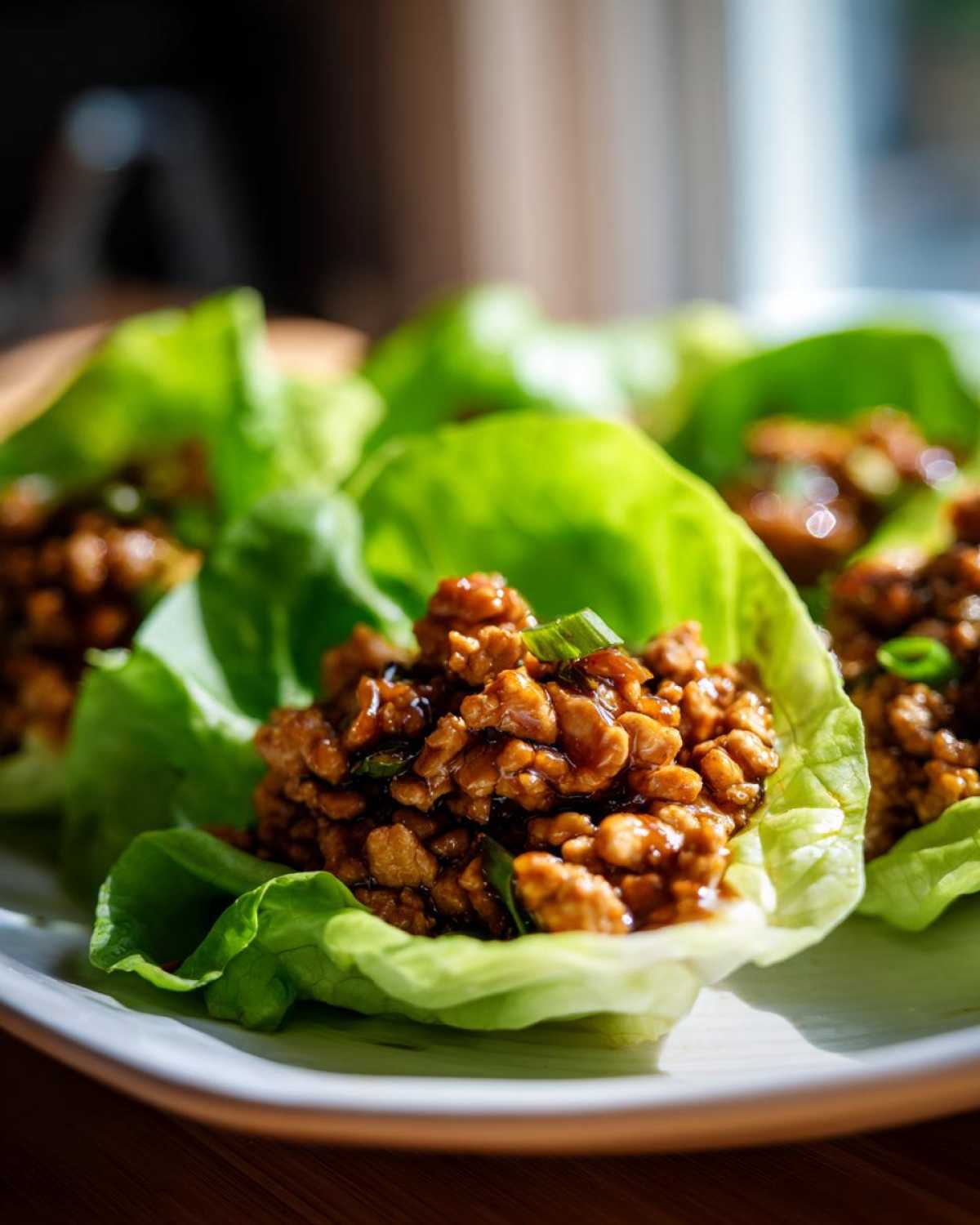 Close-up of savory, saucy ground chicken filling served in crisp lettuce cups for chicken lettuce wraps.