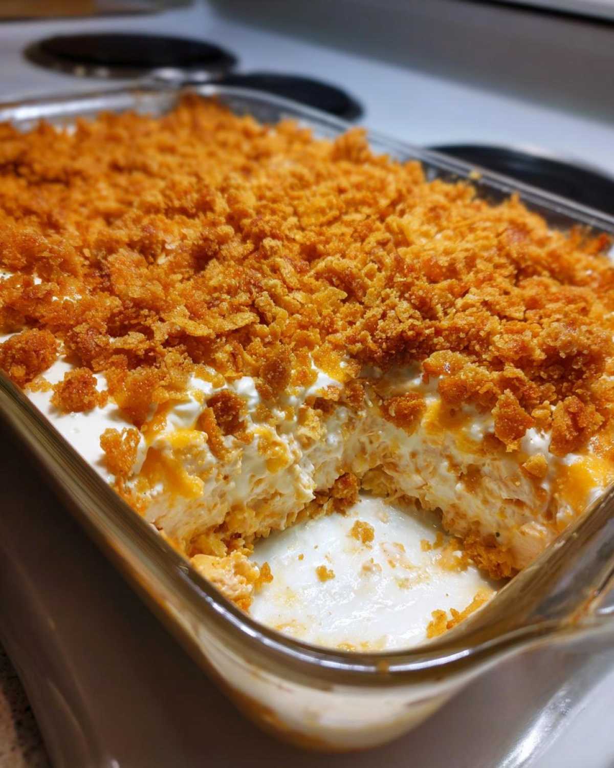 A creamy hot chicken salad casserole in a glass dish, topped with a thick layer of golden, crunchy crumbs.