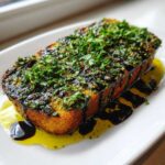 Thick slice of toasted bread generously topped with herbs, garlic, olive oil bread dip, and balsamic glaze.