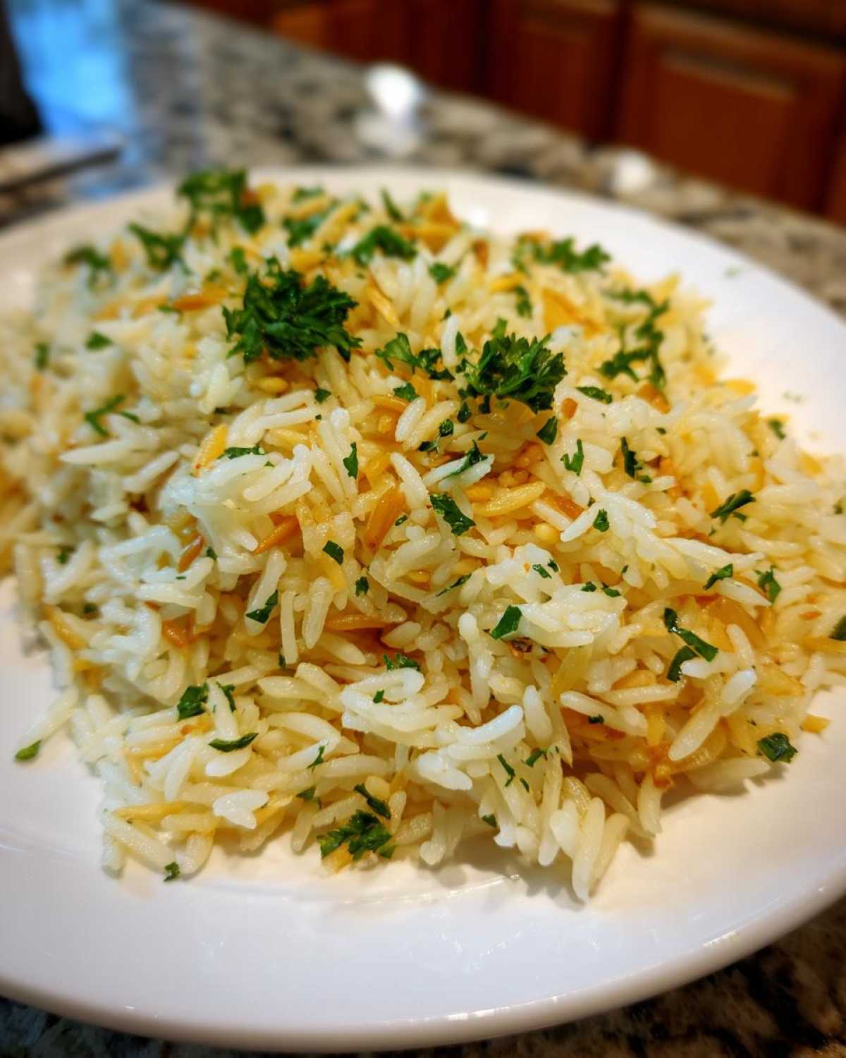 Close-up of fluffy rice pilaf mixed with toasted vermicelli and garnished with fresh chopped parsley.