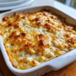 Close-up of a baked corn dip with cream cheese, featuring a bubbly, golden-brown melted cheese topping.