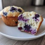 Close-up of a blueberry protein muffin cut in half showing the moist crumb and fruit.