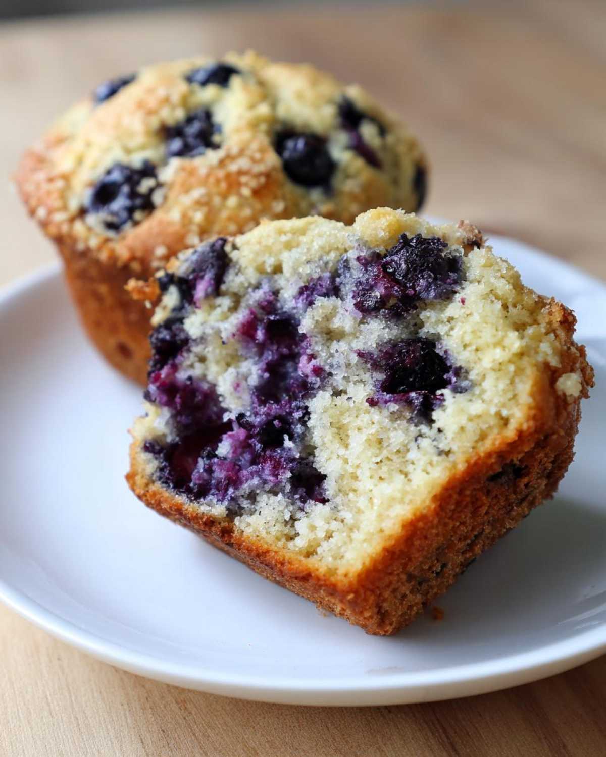 Close-up of a blueberry protein muffin cut in half showing moist crumb and burst blueberries.