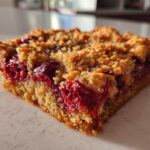 Close-up of a square slice of cherry dump cake showing the crumbly topping and bright red cherry filling.