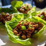 Four servings of savory chicken lettuce wraps filled with seasoned ground chicken and topped with green onions.