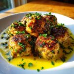 Close-up of browned chicken piccata meatballs served in a bright lemon-butter sauce with capers and fresh parsley.