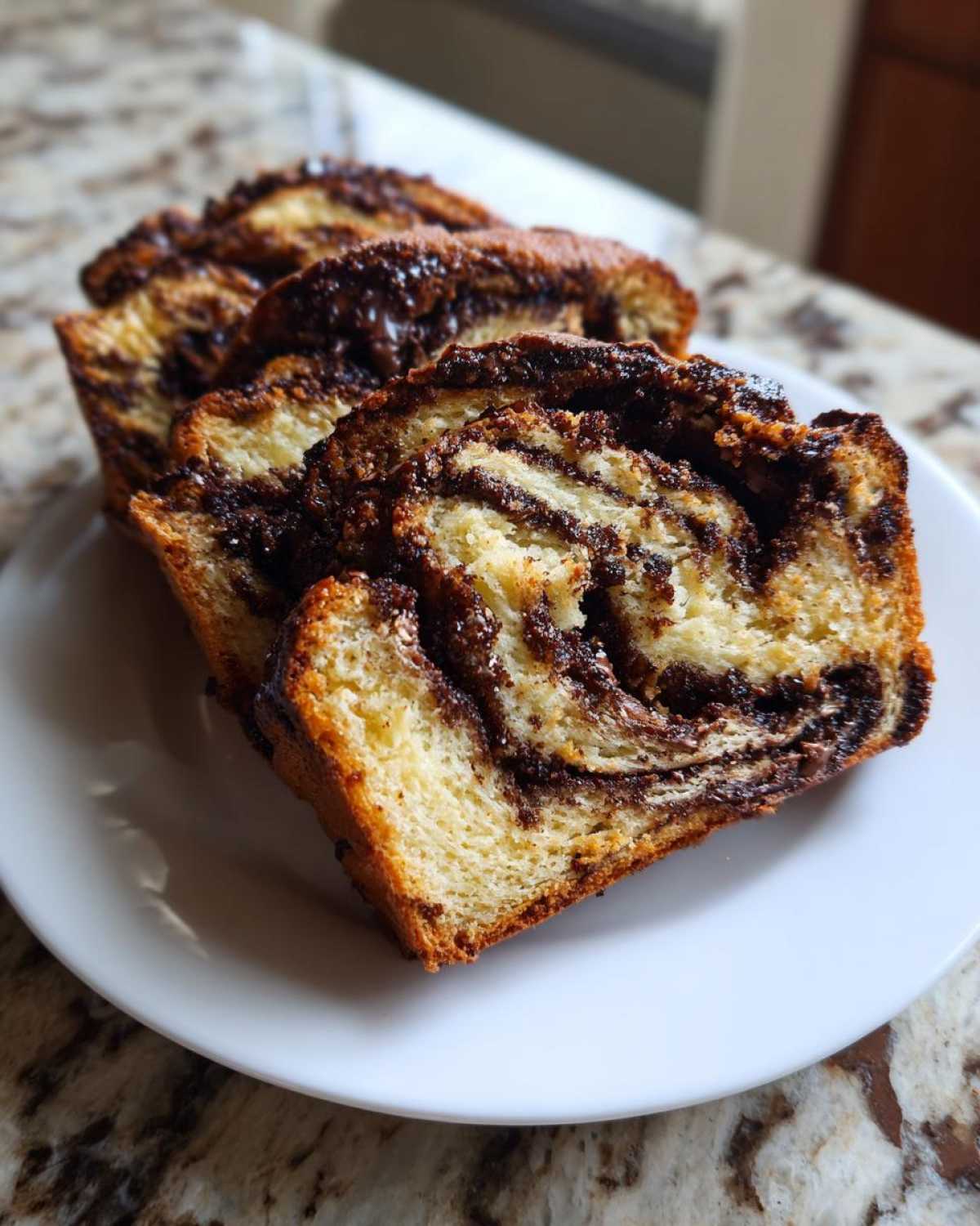Close-up of three thick slices of moist chocolate babka showing the rich, swirled chocolate filling.