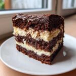 A decadent slice of chocolate Italian love cake showing three dark cake layers alternating with creamy white filling.