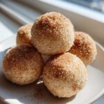 A close-up of five delicious cinnamon sugar snowball cookies heavily coated in sparkling sugar crystals.