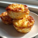 A stack of three golden-brown cottage cheese egg cups on a white plate, mimicking the Starbucks style.