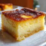 Close-up of a moist, creamy cassava cake slice showing a rich, caramelized brown top layer.