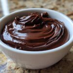 Close-up of rich, glossy, creamy chocolate dip swirled beautifully in a small white bowl.